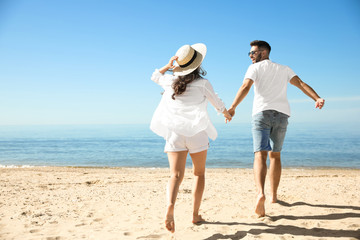 Young couple running on beach near sea. Honeymoon trip