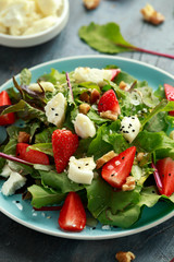 Goats cheese and strawberry summer salad served with nigella and sesame seeds drizzled with runny honey