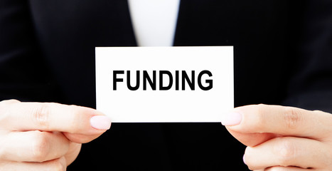 FUNDING, words on a white paper stuck out from jeans pocket. Business concept