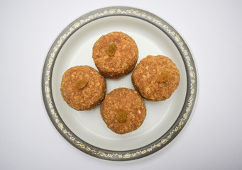 Closeup of popular Indian sweet balls Laddu or ladoo made from chapati roti powdered mashed and made in to big ball. Decorated with raisin kismis served in plate. Prashad for festivals