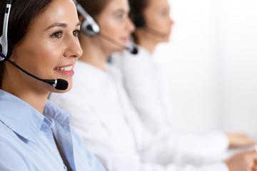 Call center. Group of operators at work. Focus on beautiful business woman in headset