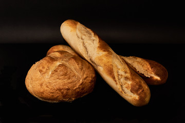 A piece of bread, with two baguettes, im a black background