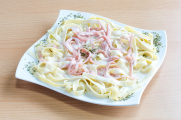 Creamy fettuccine alfredo with ham on wooden table