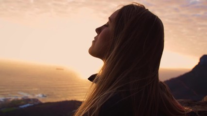 Back lit, Close up Portrait of a Young Woman in front of the ocean sunset, Meditating