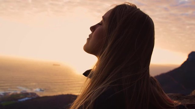 Back lit, Close up Portrait of a Young Woman in front of the ocean sunset, Meditating