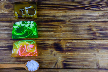 Pieces of the handmade soap and spoon with sea salt on wooden background. Top view