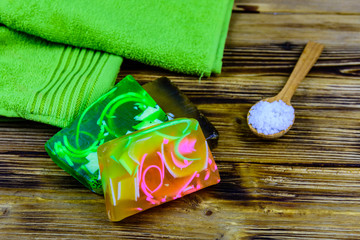 Pieces of the handmade soap, towel and spoon with sea salt on wooden background