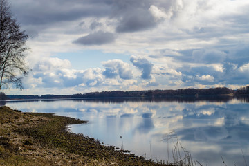Rocky bank of the Daugava River near Riga. Picturesque view. The nature of Latvia. Beautiful clouds in the blue sky and reflected in the water.