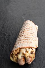 Super seeds wrap with sausages and onions cooking on black stone background