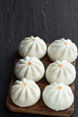 Steamed bao buns with delicious filling on black stone background