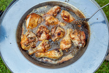 Chicken legs with crispy golden brown skin frying in hot oil