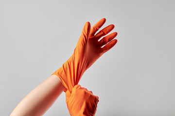 caucasian male person putting on orange washing gloves. washing and cleaning service concept....