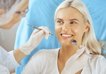 Smiling blonde woman examined by dentist at dental clinic. Healthy teeth and medicine concept