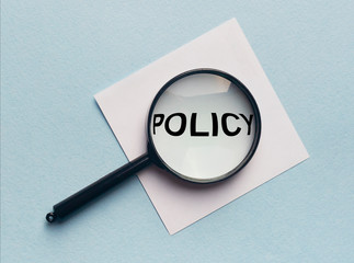word inscription policy on paper with loup lens
