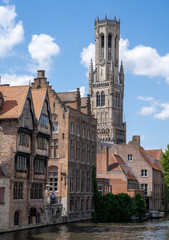 Fototapeta na wymiar Belgium, West Flanders (Vlaanderen), Bruges (Brugge). Spire of Church of Our Lady, Onze-Lieve-Vrouwekerk behind canal.