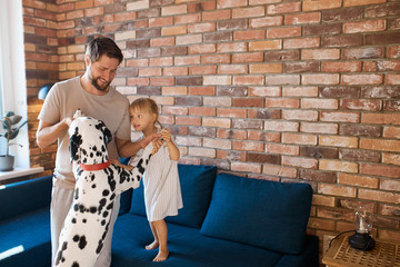 joyful man and daughter play with dog at home in living room. spend time together at weekends, holidays. smile