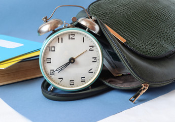 Clock with school satchel and notebooks-the concept of starting classes in educational...