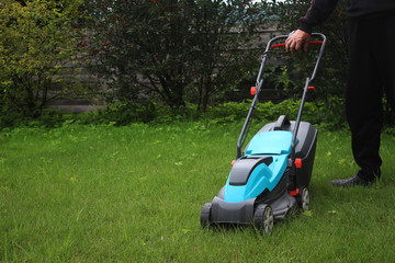 Obraz premium Lawn mowing. Man holding the handle of a lawn mower