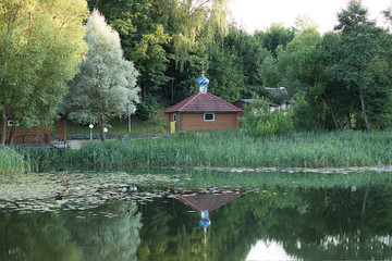 The bathhouse of the Orthodox Church is reflected in the river. Summer, Park, reeds. Symbols of...