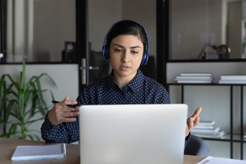 Focused young indian ethnicity speaker in headphones giving educational online lecture....