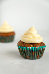 Single carrot cake muffin with icing on white background with copy space