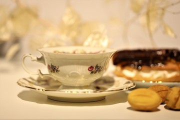 Obraz na płótnie Canvas eclair in chocolate glaze and a cup of tea on the table