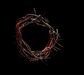 The crown of thorns lie on an isolated black background, with a red tint of light. The concept of...