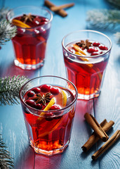 Festive mulled wine with lingonberry on a blue wooden table. Glasses of mulled wine.