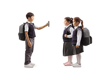 Full length profile shot of a male pupil with a smartphone showing to girls