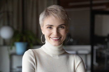Head shot profile portrait of young happy short haired blonde businesswoman in modern office....
