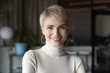 Head shot profile portrait of young happy short haired blonde businesswoman in modern office. Smiling 30s female manager, talented corporate employee, confident saleswoman looking at camera. © fizkes