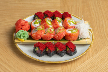 Sushi set of different rolls with tuna, salmon, shrimps, tobiko flying fish roe, ginger, daikon radish, black rice with cuttlefish and wasabi cherinles. Asian traditional food.
