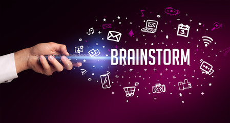 hand holding wireless peripheral with BRAINSTORM inscription, social media concept