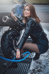 Naklejka na ściany i meble Caring about the vehicle. Attracrtive female biker in carwash service. Modern casual motorcycle.