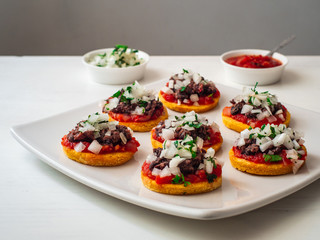 Sopes also known as Picadita, Traditional Mexican Dish That Looks like an Unusually Thick Tortilla with Toppings like Tomato Sauce, Refried Beans, Raw Onion, Cilantro