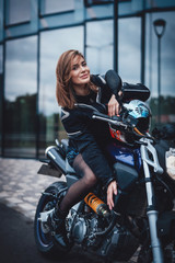 Fototapeta na wymiar A nice looking woman at the streets with her urban sport motorcycle. Motorbike sport hobby. Modern custom bike.