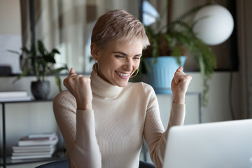 Emotional overjoyed 30s young blonde businesswoman looking at computer screen, celebrating...