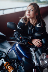 Fototapeta na wymiar Sunny photo of female biker and motorcycle. Urban motosport hobby. Motosport passion.