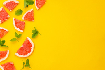 Summer colorful background with gapefruit slices on yellow background with copy space. Lemonade or fruit drink concept.