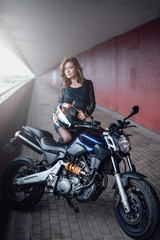Naklejka na ściany i meble A nice looking girl with her casual modern bike. Urban motosport hobby. Brown-hair female driver.
