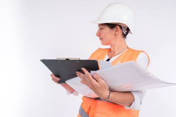 Woman engineer. Engineer with many papers in his hands. Woman in an orange canopy and a protective helmet. Clipboard and paper in hands of a woman builder. Concept - career of engineer or builder