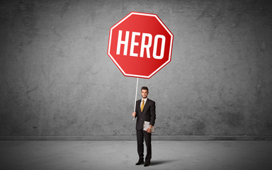 Young business person holding road sign with HERO inscription, new rules concept