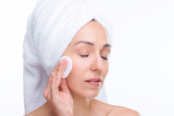 Young fresh beautiful woman with cotton pad applying purifying lotion on face