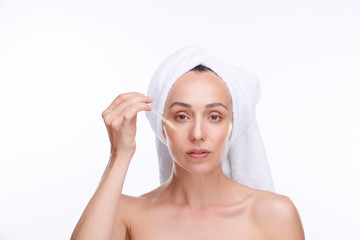 Young woman with white towel on head going to apply rejuvenating serum on face