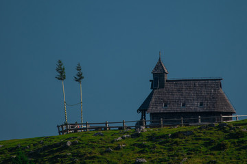 Fototapeta premium Typical old wooden chapel on the top of the hill on Velika planina, a mountain plateau in central Slovenia on a warm summer day.