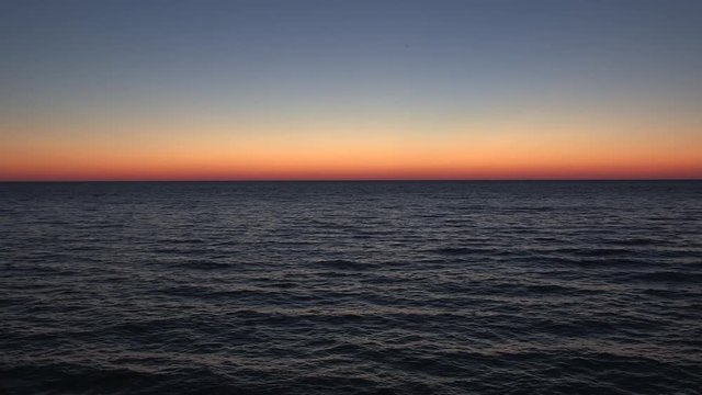 Scenic skyline gradient red orange blue green yellow clear sky no clouds calm waves and Lake Huron wide ontario