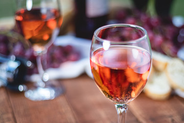 Close up of a glass of wine on a table with grapes and wine bottle blurred in the background