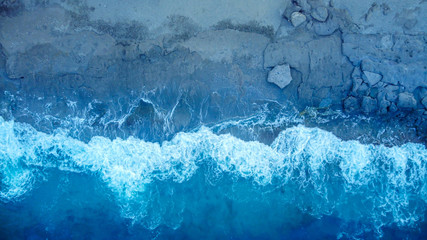 Aerial view at the sea with waves at a sunrise. Directly above the sea camera.