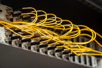 Many yellow fiber optic cables are inserted into the switches in multiple rows. Cable management....