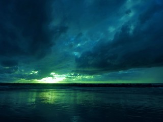 Fototapeta na wymiar Sun sets behind the clouds into the sea